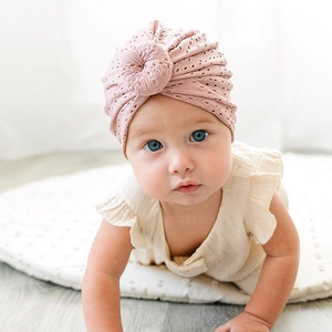 Close-up of pink baby turban hat with breathable hollow-out design and top knot detail
