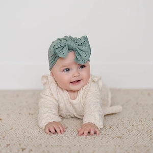 Détail du turban pour bébé en tissu ajouré vert sauge respirant avec un grand nœud doux