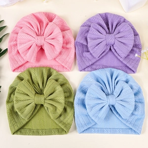 Détail de la texture côtelée et du grand nœud sur les turbans bébé en quatre couleurs