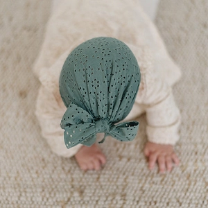 Détail du bonnet turban bébé avec nœud en maille ajourée vert sauge vintage
