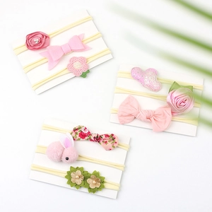 Detail of three sets of pink baby nylon headbands with floral and bow decorations