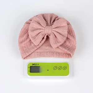 Bonnet turban en tricot rose pour bébé pesant 32,6 g, montrant une texture douce et légère
