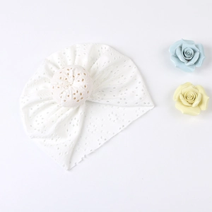 Close-up of white baby donut hat with intricate floral embroidery and breathable lace
