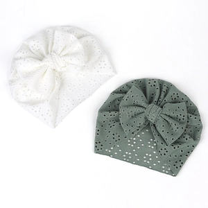 Détail de turbans pour bébé avec broderie anglaise et grands nœuds décoratifs