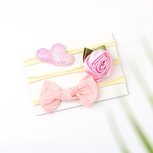 Detailed view of three-piece pink baby nylon headbands with floral and sequin heart bow