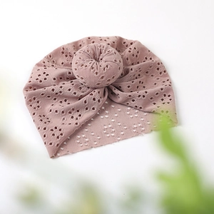 Detail of baby donut hat in dusty pink featuring breathable hollow knit and top knot