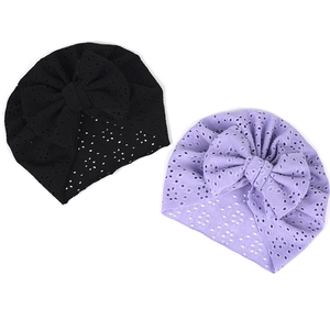 Détail de bonnets turban pour bébé en broderie anglaise avec grands nœuds décoratifs