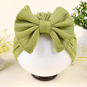Détail du turban pour bébé en maille côtelée verte avec un grand nœud élégant