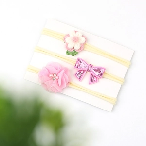Detailed close-up of three baby headbands with pink crochet flowers and sequin bows