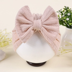 Détail du bonnet turban rose pour bébé avec maille gaufrée et grand nœud décoratif