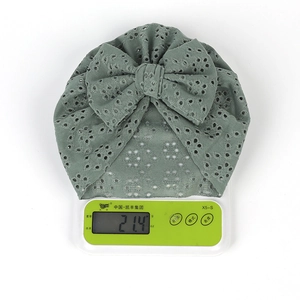 Détail montrant le bonnet turban pour bébé léger pesant 21,4g sur une balance