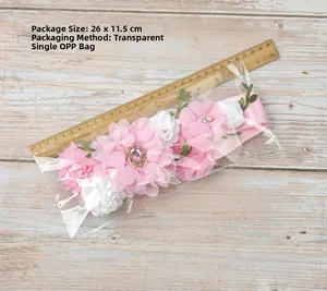 Detail of baby shower flower belt with pink rhinestones and green leaf accents