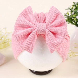 Vue détaillée du turban pour bébé avec grand nœud et texture en tricot rose doux