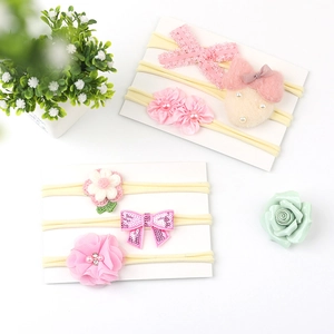 Close-up of pink baby headbands with lace bows, satin flowers, and plush bunny details