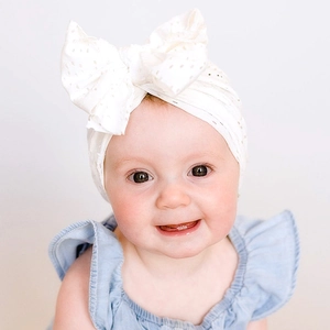 Bandeau blanc pour bébé avec grand nœud et détails de broderie florale évidée