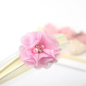Detail of pink chiffon flower baby headband with pearls and rhinestones on beige elastic
