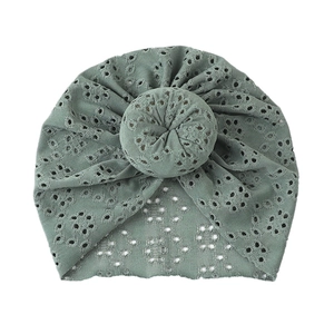 Detail of green baby turban hat with hollow lace embroidery and doughnut top knot