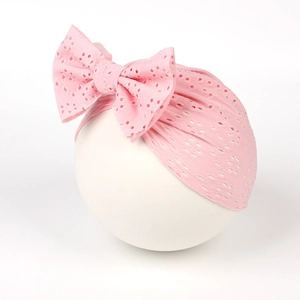 Bonnet bébé rose respirant en dentelle ajourée orné d'un grand nœud décoratif élégant