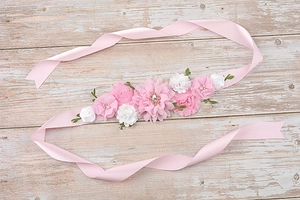 Detailed macro of pink and white handmade flowers with rhinestones on pregnancy sash