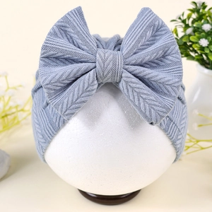 Détail du bandeau bébé avec motif tricoté en chevron et grand nœud décoratif assorti