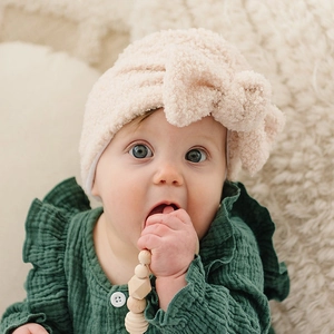 Détail d'un bonnet bébé en polaire beige avec un grand nœud et texture douce