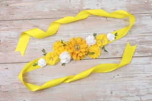 Detail of floral maternity sash with yellow fabric flowers and a central gemstone