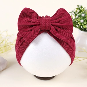 Détail du bonnet turban bordeaux pour bébé avec grand nœud tricoté sur mannequin blanc