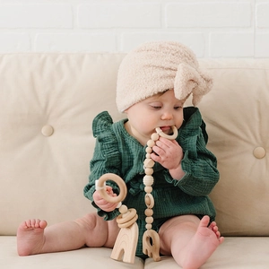 Bonnet bébé en polaire avec noeud et barboteuse verte à volants avec jouet en bois