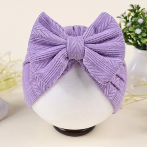 Détail du bonnet turban bébé en tricot violet à motif épi avec un grand nœud décoratif