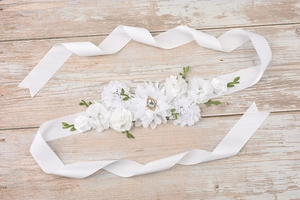 Close-up of white fabric flowers with pearls and rhinestones on a satin sash belt