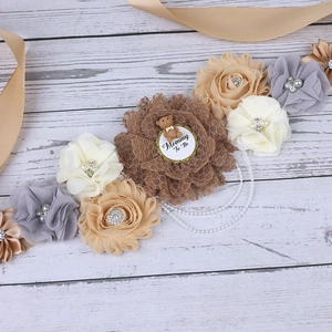 Close-up of floral maternity sash with Teddy bear and Mommy To Be charm for party