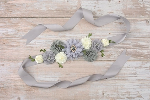 Detailed close-up of handmade floral satin belt with fabric roses and leaf accents