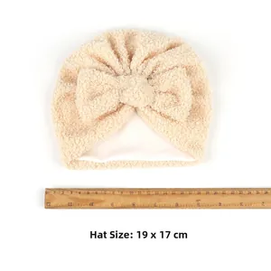 Détail du bonnet bébé en polaire beige avec nœud, taille 19x17 cm avec règle de mesure