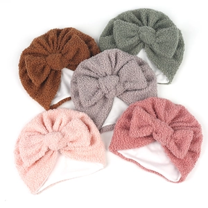 Détail de cinq bonnets turban en polaire pour bébé avec gros nœud et doublure coton