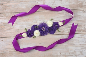 Close-up of elegant purple floral maternity sash with satin ribbon and jewel detail