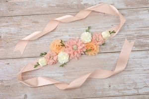 Macro detail of maternity sash with satin flowers, rhinestones and green leaves