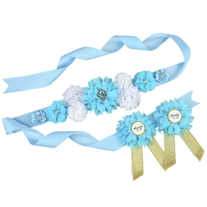Detail of baby shower flower sash and Mommy to Be badges in blue and white colors
