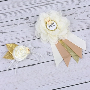 Close-up of Daddy To Be badges with lace, bear detail and white roses for baby shower party