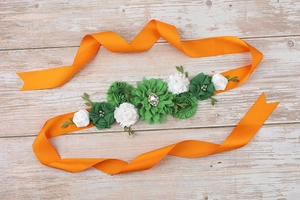 Macro shot of pregnancy belly belt with green fabric flowers and orange satin ribbon