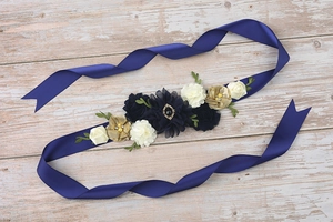 Detail view of navy blue satin belt with handcrafted fabric flowers and pearl accents
