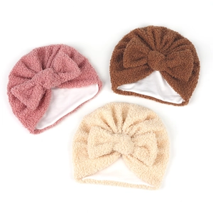 Vue détaillée de bonnets bébé à nœud en peluche rose, marron et beige avec doublure douce