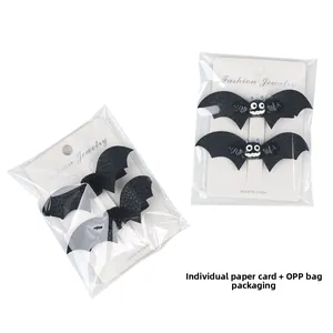 Detail view of two pairs of black bat leather hair clips with cute eyes on packaging cards
