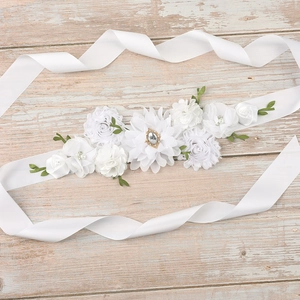 Detailed view of handmade white fabric flowers with rhinestones on a satin sash belt