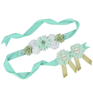 Close-up of mint green maternity sash and flower badges with Mommy To Be gold lettering