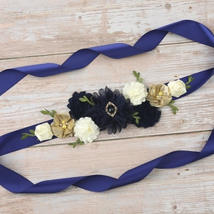 Detail of navy blue satin sash with handmade floral clusters and sparkling rhinestones
