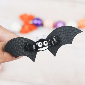 Detail of Halloween bat hair clip with black faux leather wings and purple horns