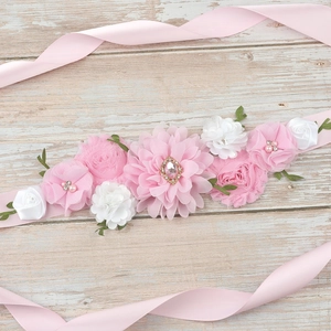 Detail of pink chiffon flowers and large rhinestone on a maternity sash for parties