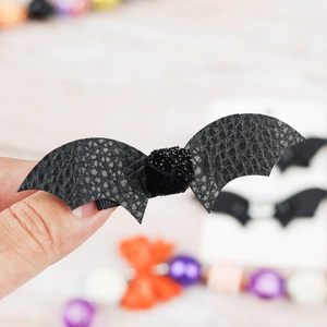Detail of bat-shaped Halloween hair clip with faux leather texture and glitter center