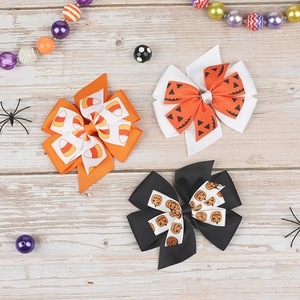 Detailed close-up of three Halloween layered grosgrain ribbon hair bows with pumpkin prints