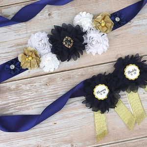 Detail of navy flower maternity sash and Mommy Daddy To Be pins on wood surface